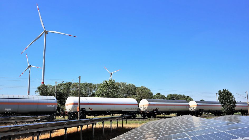 Druckgaskesselwagen fahren zwischen Windrädern und Photovoltaikanlagen hindurch