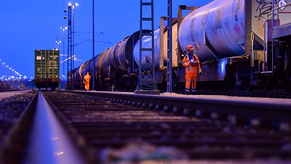 Tankcontainer und Kesselwagen im werden am Rangierbahnhof von einem Wagenmeister kontrolliert
