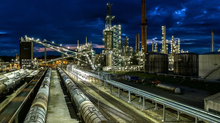 Raffinerie mit Gleisen bei Nacht