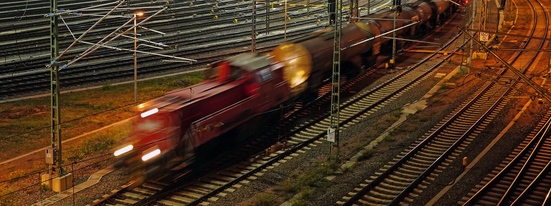 Schneller Zug mit Kesselwagen fährt aus dem Rangierbahnhof Halle bei Nacht 