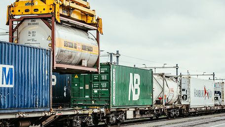 Zug mit Kesselwagen und Containern wird per Kran beladen