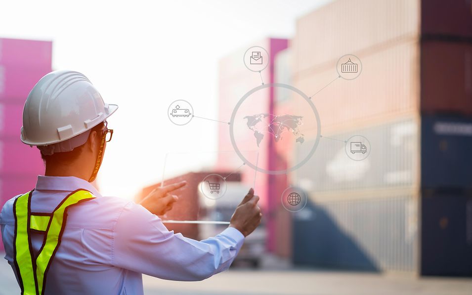 Logistik-Mitarbeiter visualisiert Datentransfer vor einem Container-Depot.