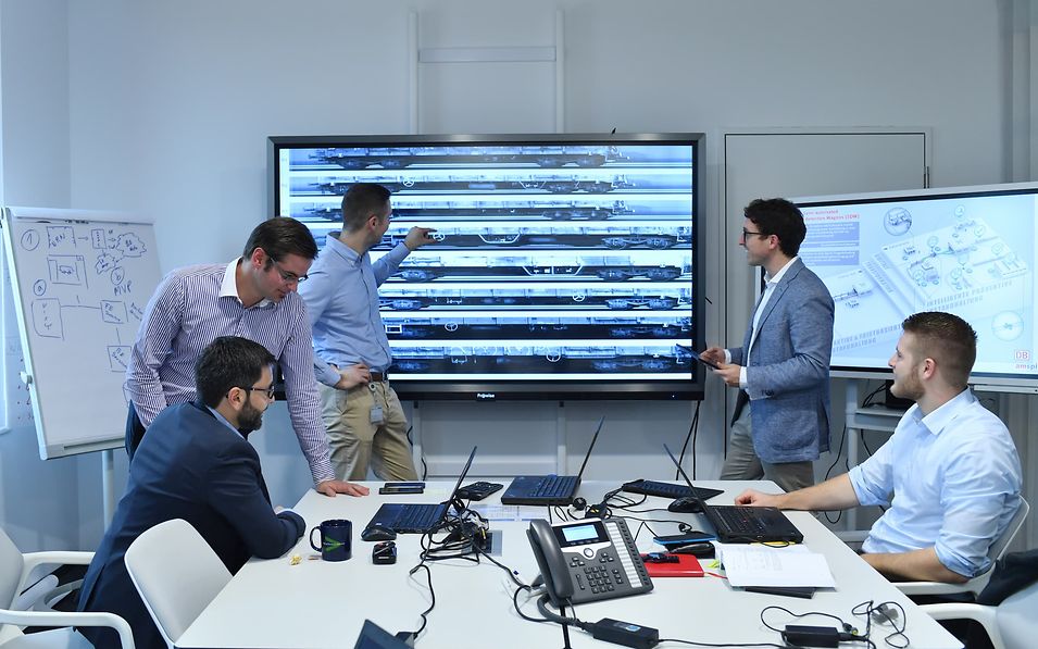 Fünf Mitarbeiter vor Smartboard.