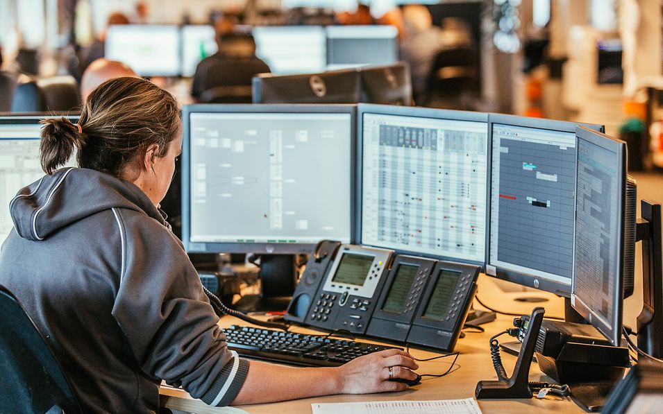 Mitarbeiterin sitzt vor vier Bildschirmen.