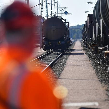 DB-Mitarbeiter schaut auf stehende Züge am Gleis