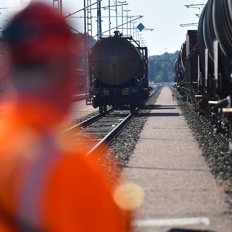 DB-Mitarbeiter schaut auf stehende Züge am Gleis