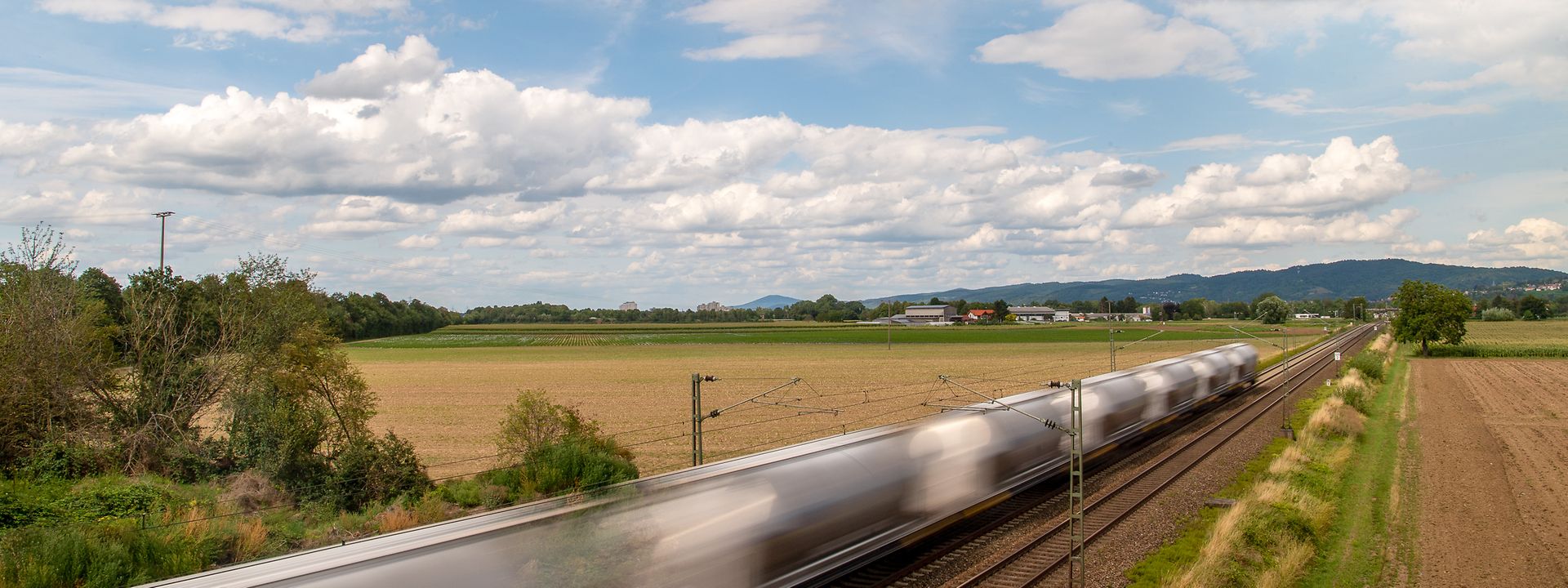 A shuttle train speeds through the countryside.