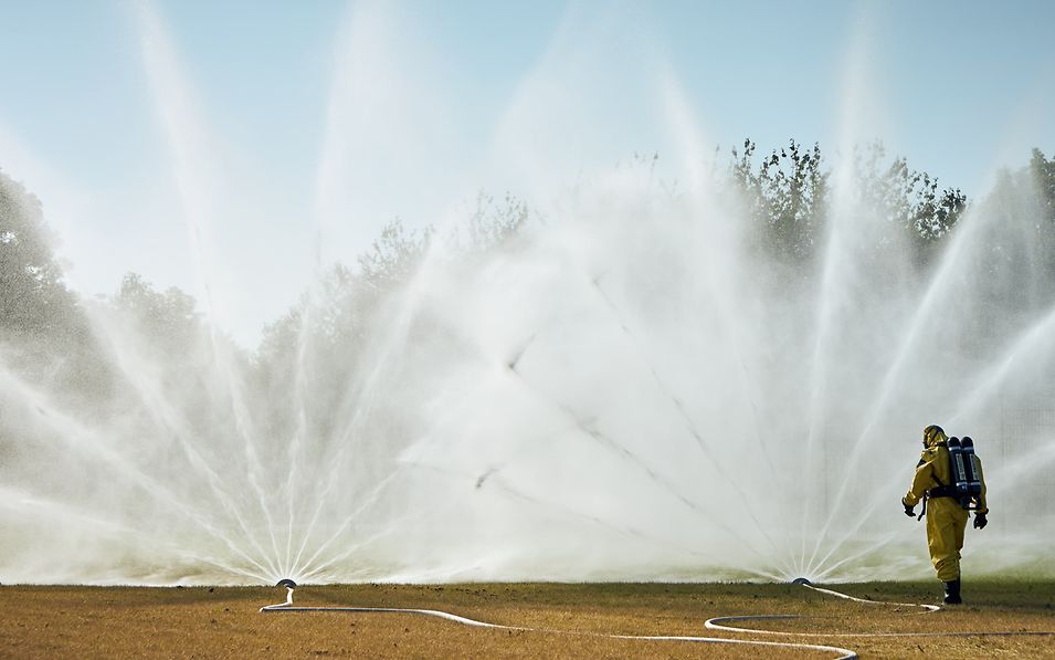 Person in safety clothing walks towards a sprinkler system.