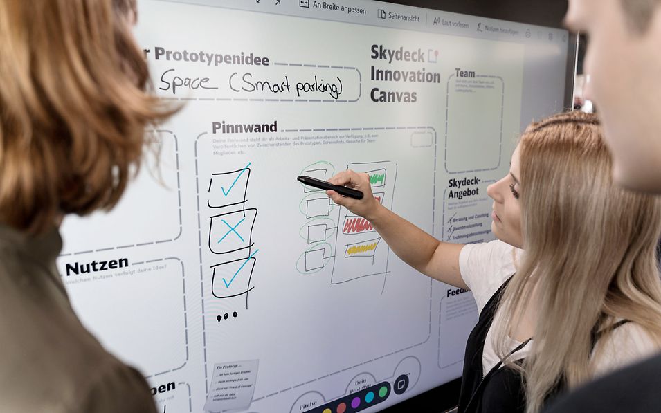 Three people in front of a smartboard.